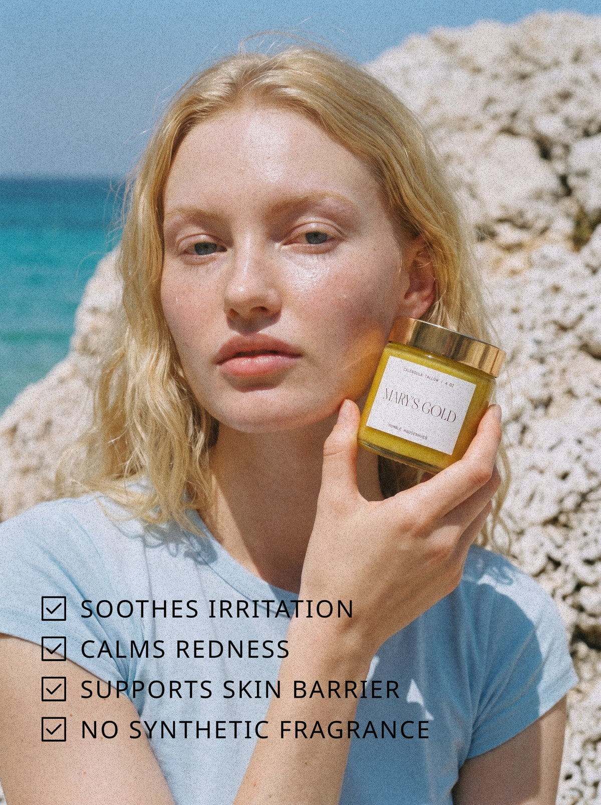 A woman by the sea holding the Mary's Gold Calendula Tallow jar. Text: soothes irritation, calms redness, supports skin barrier, no synthetic fragrance.